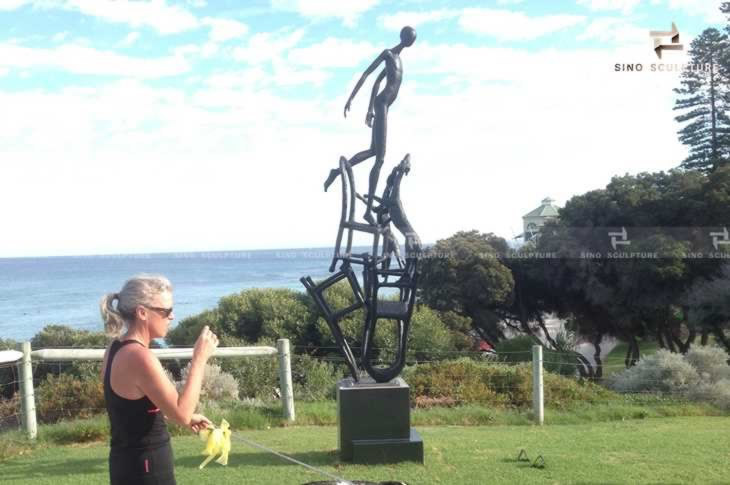 Visitor passing by the casting bronze sculpture exhibited sculpture by the sea