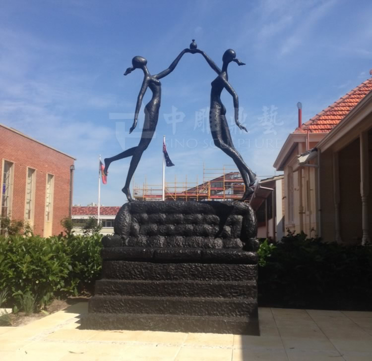 2 bronze casting girls sculptures standing on a bronze casting sofa