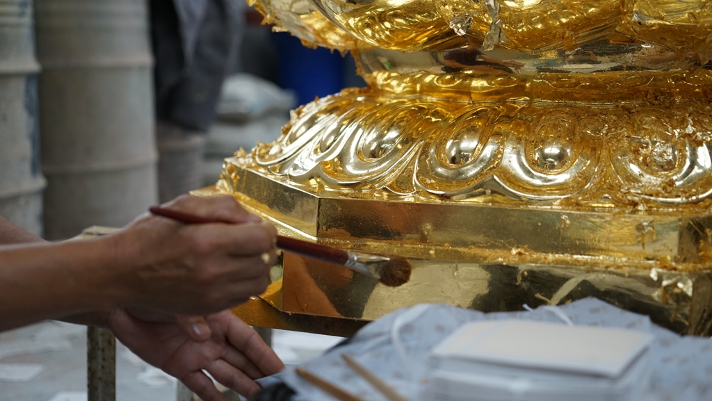 The craft of gold leaf on Buddha Statue