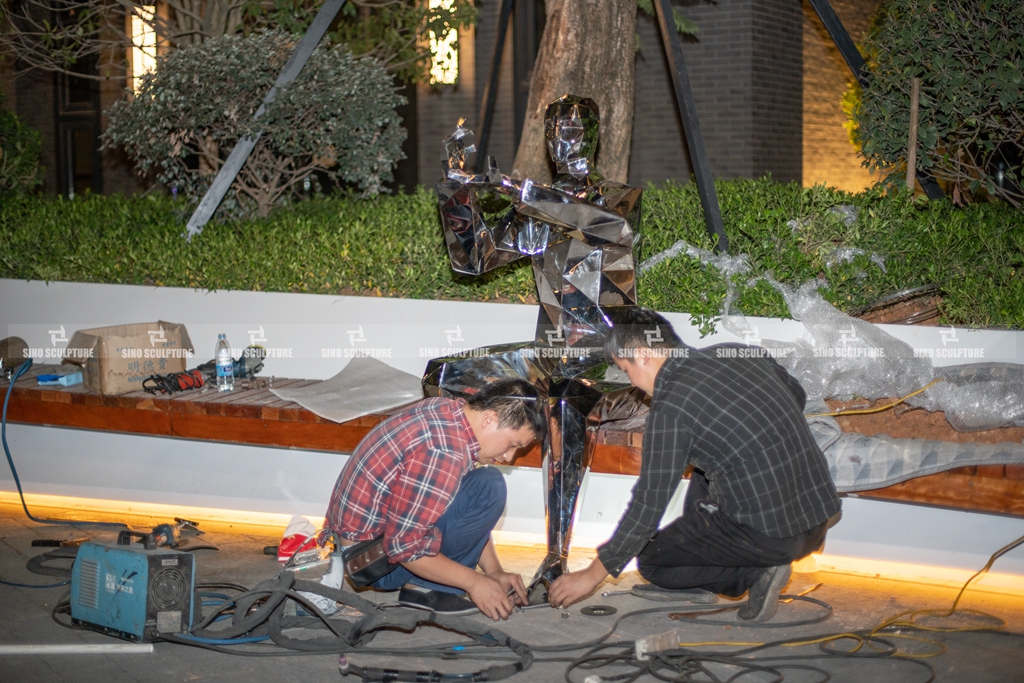 Site installation of the mirror finish steel statue sculpture